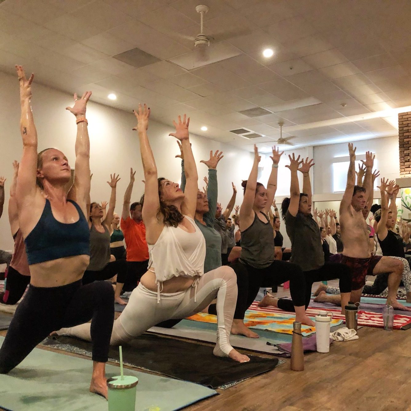 a full classroom of students with their hands raised to the sky and their front legs bent in a standing pose