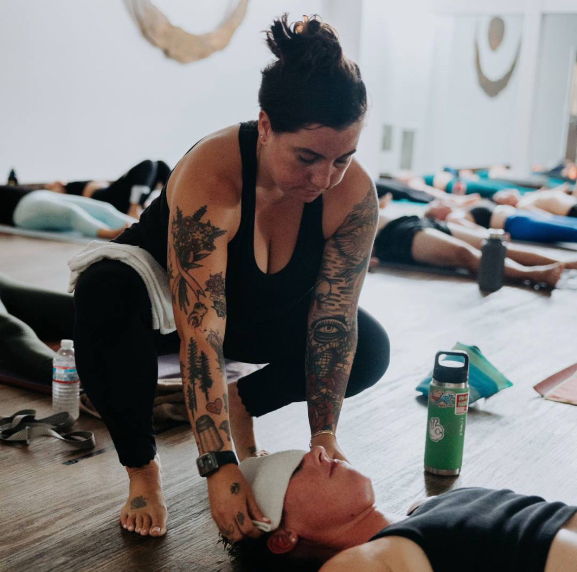 Yoga instructor placing towel to cover student's eyes in rest pose